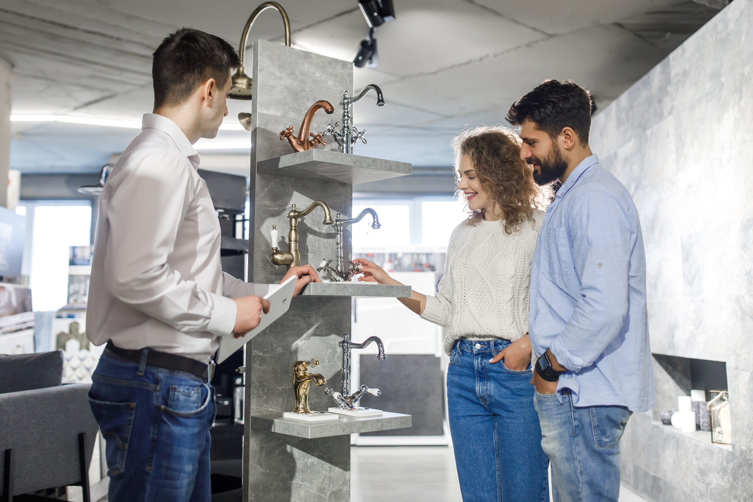 Positive cute couple choosing tap in the bath in bathroom furniture shop.